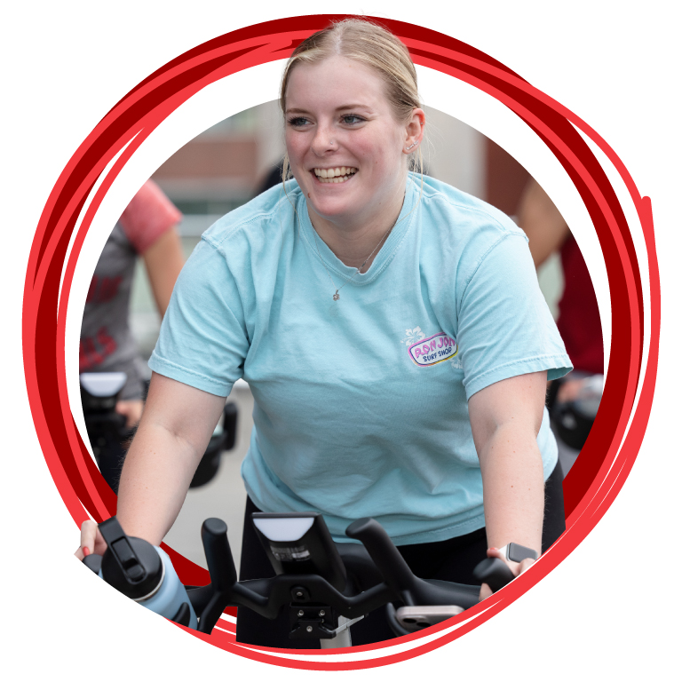 A student on a stationary bike smiling.